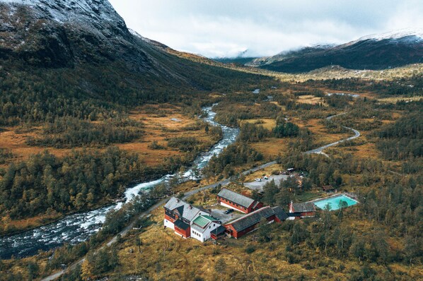 Vista aérea de una zona rural con un río, edificios y una piscina.