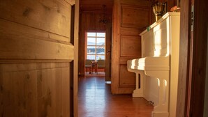 Un pasillo de madera con vista a un comedor y una ventana que da a un paisaje nevado.