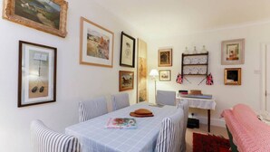 Un comedor con una mesa dispuesta para dos personas, sillas a rayas y una alfombra roja.
