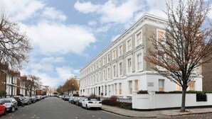Una hilera de casas urbanas blancas con una calle pavimentada en el medio.