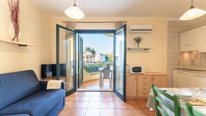 A modern apartment with a living room, kitchenette, and a balcony with a view. - One bedroom apartment (4 people) - Residence I Mirti Bianchi (Santa Teresa Gallura)