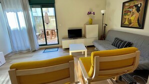A living room with a sofa, yellow armchairs, a television, a small table, and a painting on the wall. - Apartment/ flat - Coruña (O Pindo)