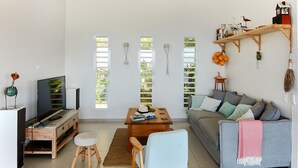 Un salon comprenant un canapé, une table basse, un meuble pour la télévision et une étagère en bois ornée d’objets décoratifs.