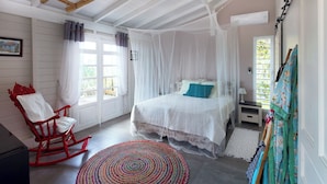 Une chambre à coucher avec un lit, un fauteuil à bascule, un tapis coloré et un portant à vêtements.