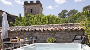 A hot tub with a stone wall and a tower in the background. - Charming detached house for 2 with private jacuzzi. Prestige & design. (Carnas)