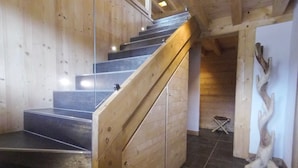 A wooden staircase with a glass balustrade leading to a landing.