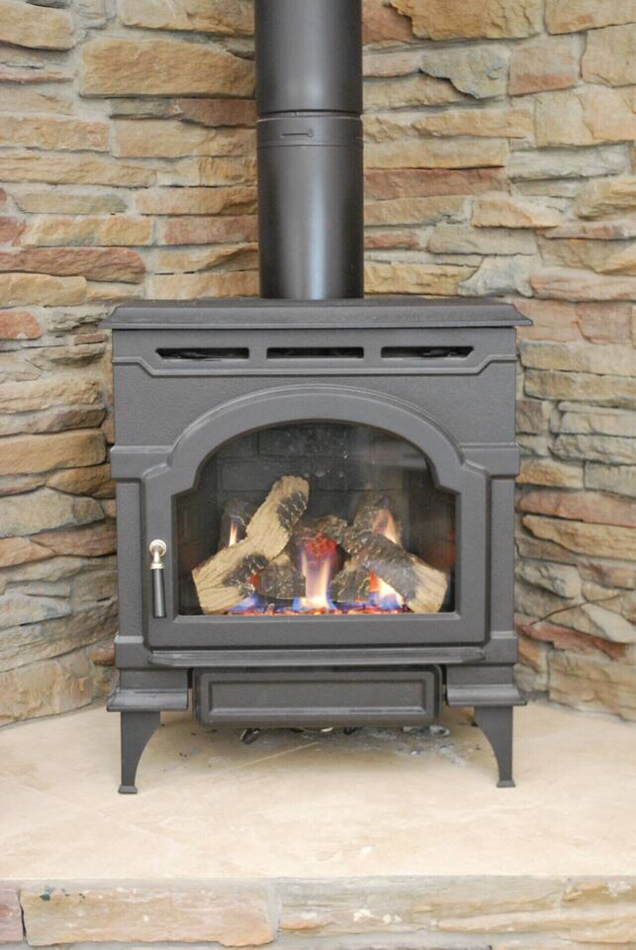 A wood-burning stove with a stone wall background.