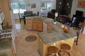 Una cocina con encimera de granito, armarios de madera y una isla integrada con taburetes.