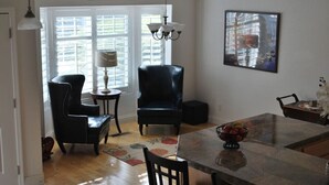 A dining area with a table, chairs, a chandelier, and a painting on the wall.