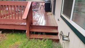 A wooden deck with steps leading to a covered patio area.