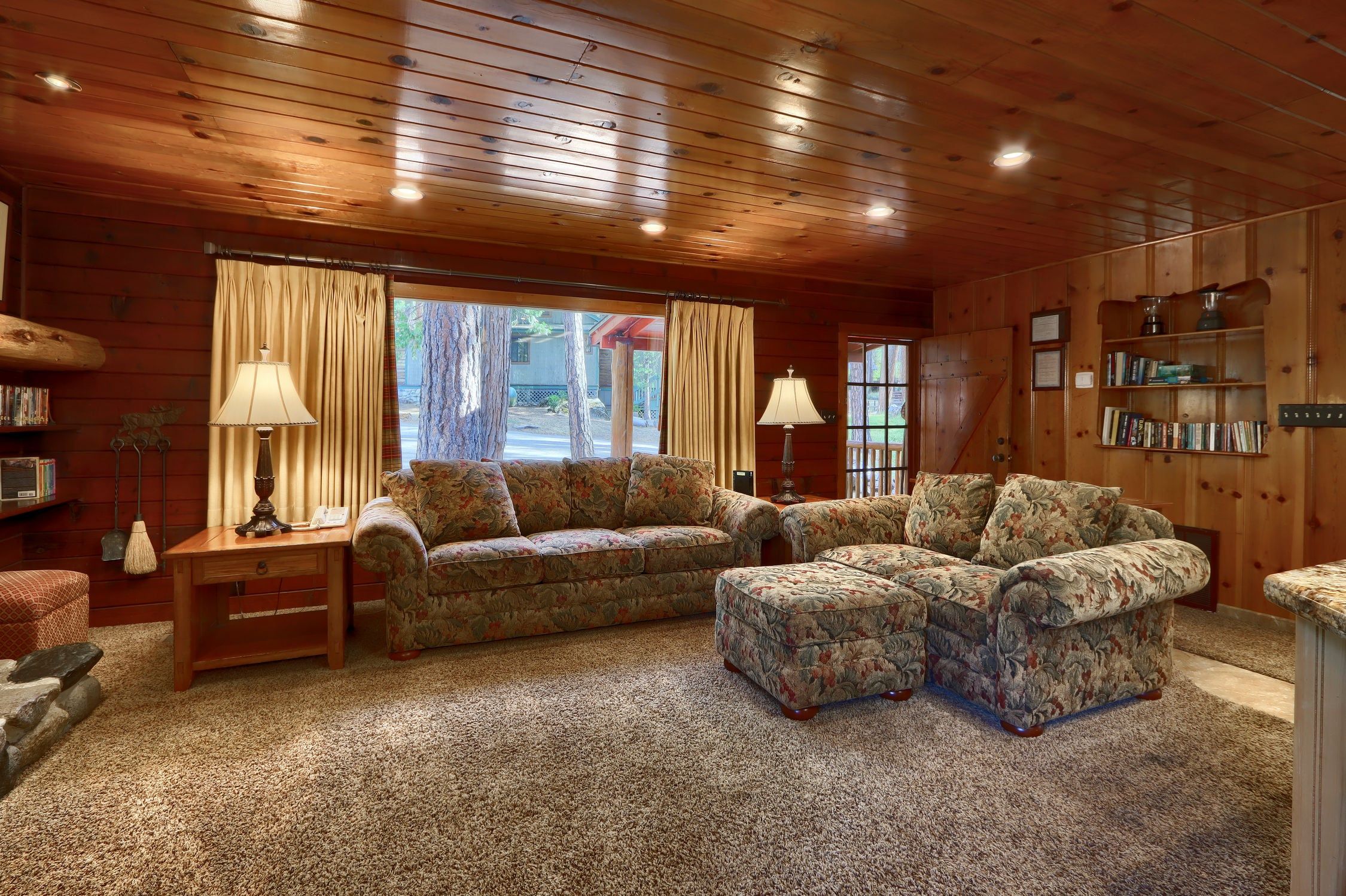 A cozy living room with a wooden ceiling, two sofas, a coffee table, and a bookshelf.