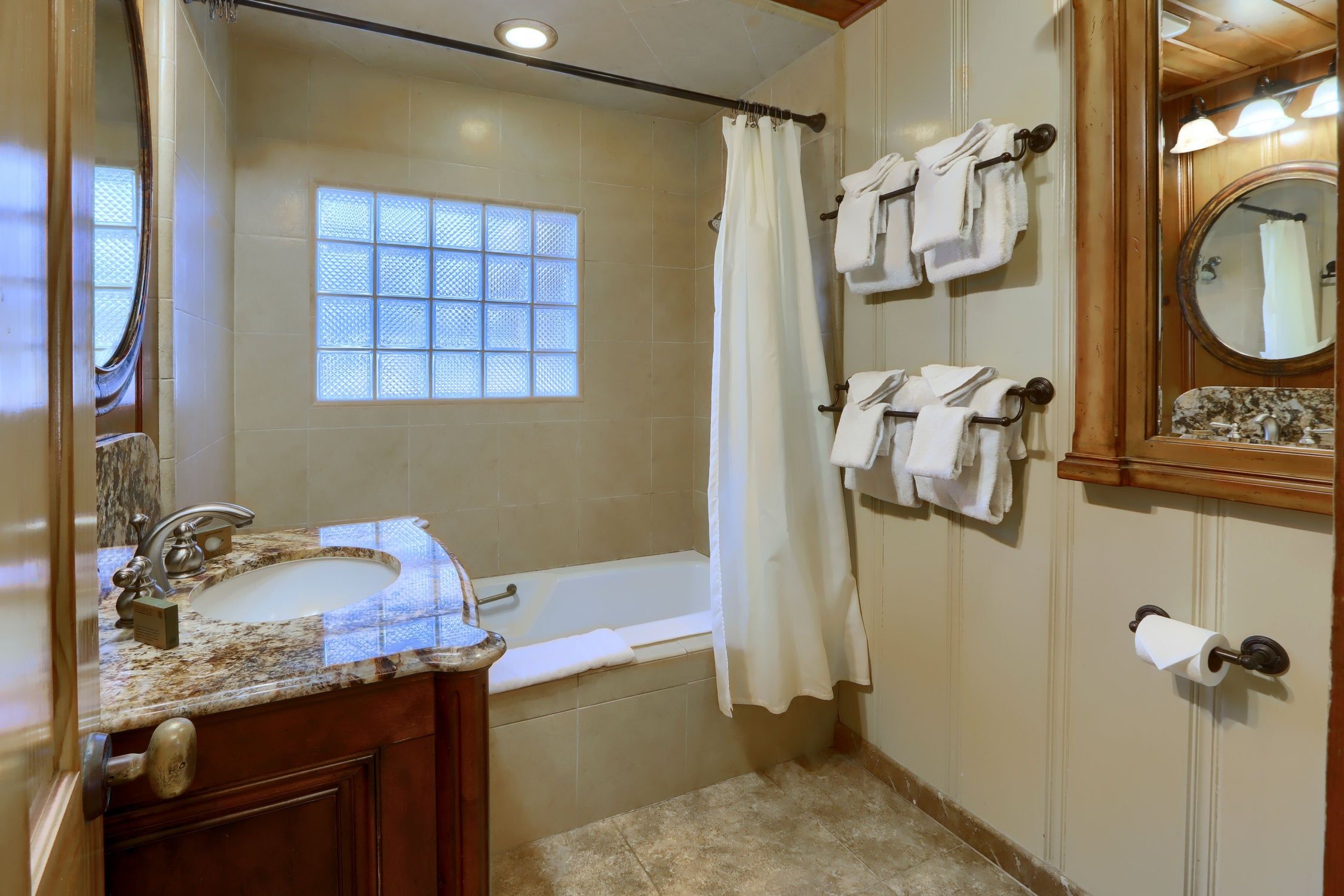 Ein Badezimmer mit Waschbecken, Spiegel, Badewanne und Handtuchhalter.
