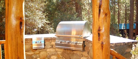 An outdoor grill setup with a stone wall and wooden posts.