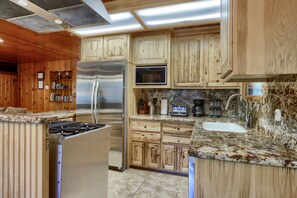A kitchen with wooden cabinets, stainless steel appliances, a granite countertop, and a built-in microwave.