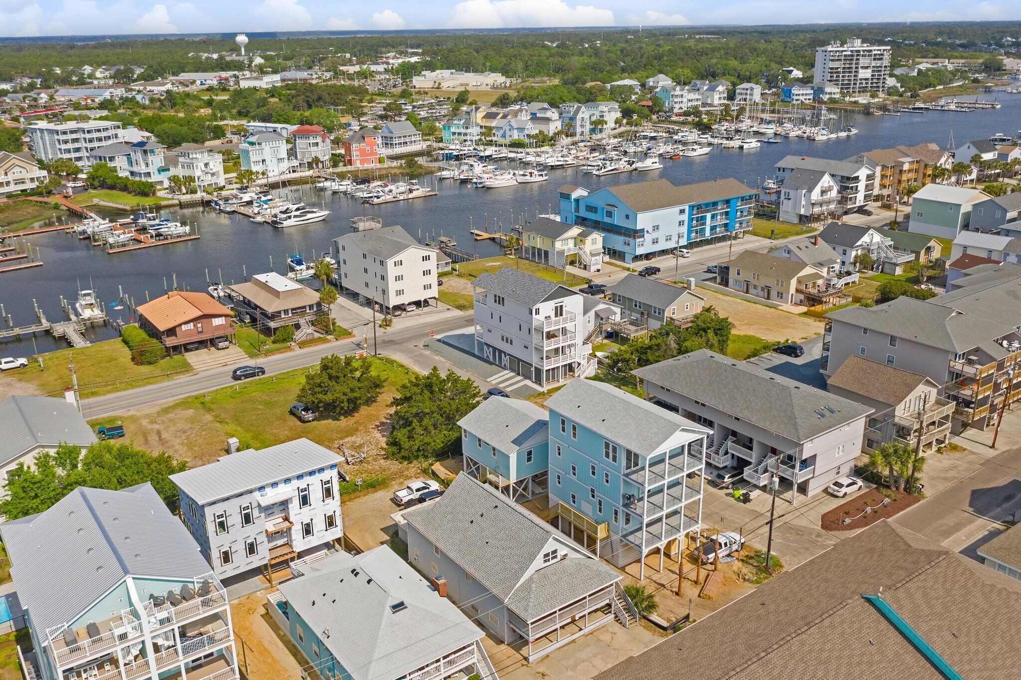 Un pueblo costero con edificios residenciales, un puerto deportivo con barcos y una vista despejada del agua.