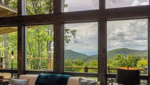 A room with a large window overlooking a forested mountain landscape. - Bella Vista - Views! Views! Views! (Highlands)