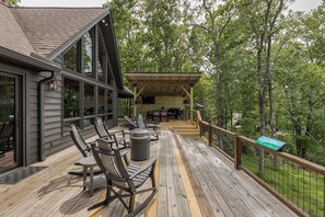 Une terrasse en bois avec des sièges d’extérieur, une pergola et une vue sur la forêt environnante.