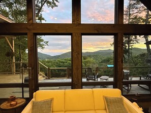 A yellow sofa with a view of a deck and mountains through large windows. - Bella Vista - Views! Views! Views! (Highlands)