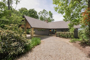 A modern house with a gravel driveway, surrounded by lush greenery and trees. - Bella Vista - Views! Views! Views! (Highlands)
