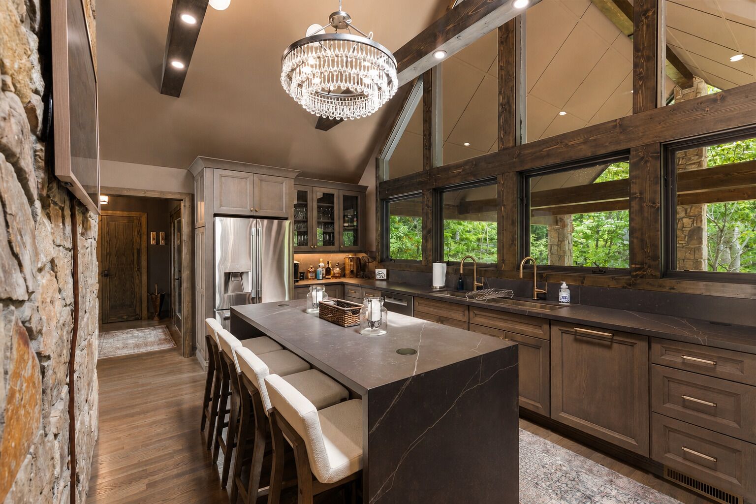 A kitchen with a large island, wooden cabinets, and a stone wall.