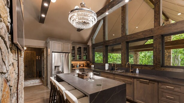 A kitchen with a large island, wooden cabinets, and a stone wall. - Bella Vista - Views! Views! Views! (Highlands)