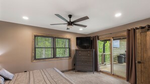 A bedroom with a bed, a ceiling fan, a dresser, a TV, and a sliding glass door leading to an outdoor area. - Bella Vista - Views! Views! Views! (Highlands)