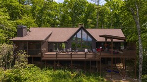 Une cabane dotée d’une terrasse, de grandes fenêtres et d’une cheminée.