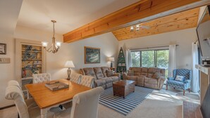 A cozy living room with a wooden ceiling, a dining table with chairs, and a fireplace. - The Lions Den Pt. II by Innsbrook Vacations! (Innsbrook)