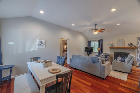 A spacious living room with a fireplace, a dining area with a white table and blue chairs, and a grey sofa. - Lake Aspen Retreat by Innsbrook Vacations! (Innsbrook)