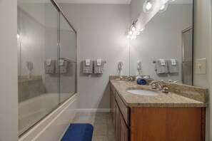 A modern bathroom with a glass-enclosed shower, a vanity with a sink and mirror, and multiple towels. - Lake Aspen Retreat by Innsbrook Vacations! (Innsbrook)