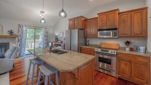 A modern kitchen with wooden cabinets, stainless steel appliances, and a large island with bar stools.