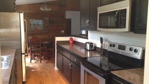 A kitchen with wooden walls, a stainless steel refrigerator, a microwave, a toaster, and a stove. - River Access and just 3.5 miles from Downtown Franklin (Franklin)