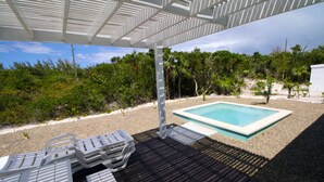 Un espacio al aire libre cubierto con piscina, sillones de descanso y una pérgola.