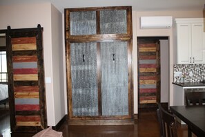 Cuina amb una porta de fusta, armaris blancs i un rebedor de rajola.