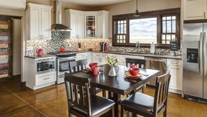 A modern kitchen with white cabinets, a stainless steel refrigerator, and a large window offering a mountain view. - Lone Cactus Ranch House Cottage Paradise Valley (Pray)