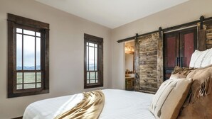 A bedroom with a large bed, two windows, and a wooden door. - Lone Cactus Ranch House Cottage Paradise Valley (Pray)