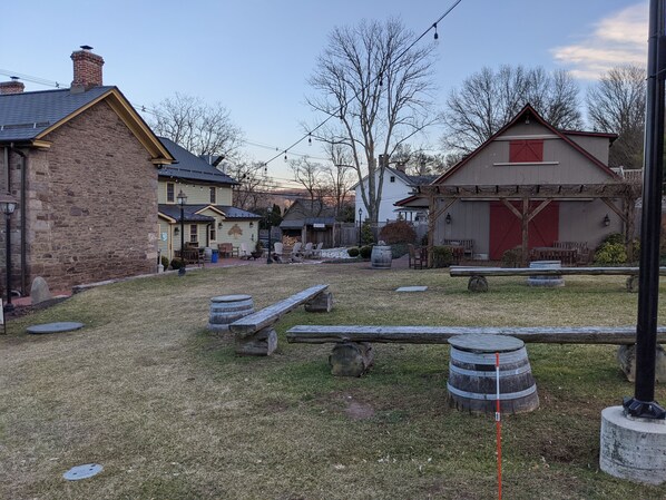Un espacio al aire libre rústico con edificios de piedra, bancos de madera y barriles.