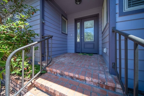 Enter a charming home through the inviting brick-paved porch and dark-colored door with a glass panel.