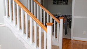 A staircase with white railings and wooden handrails leading to a room with a foosball table. - Large 3 BR 2.5BA Lake Norman House in Birkdale Village,Close to Charlotte! (Huntersville)
