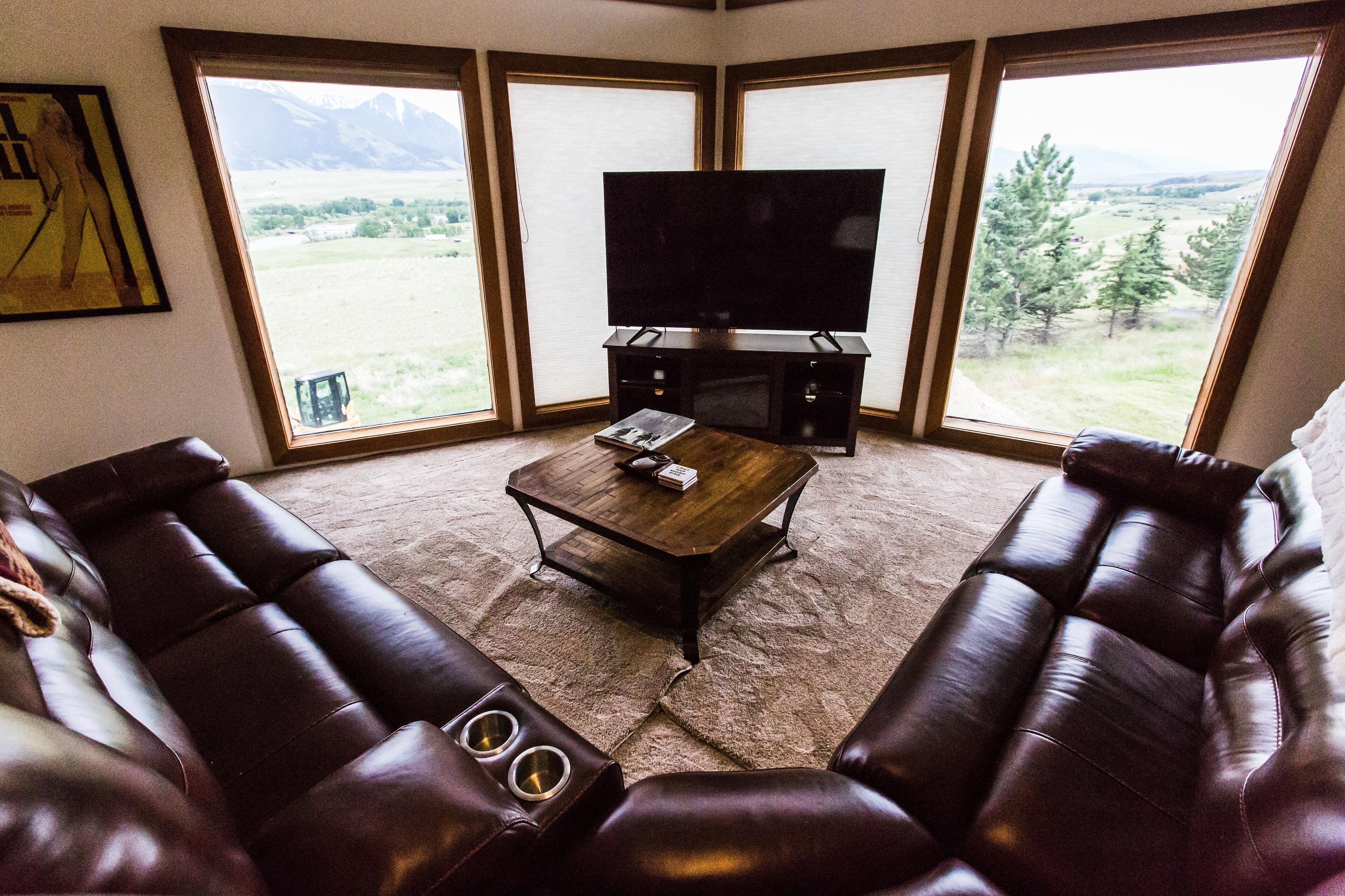 A living room with a large flat-screen TV, leather sofas, a coffee table, and a fireplace.