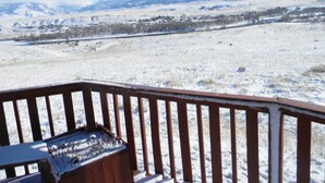 Paisagem nevada com um deck de madeira e uma montanha ao fundo.