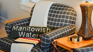 A cozy room with a plaid armchair, a map on the wall, and a lamp on a wooden side table.