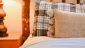 A bed with a wooden headboard, a plaid pillow, and a textured pillow.