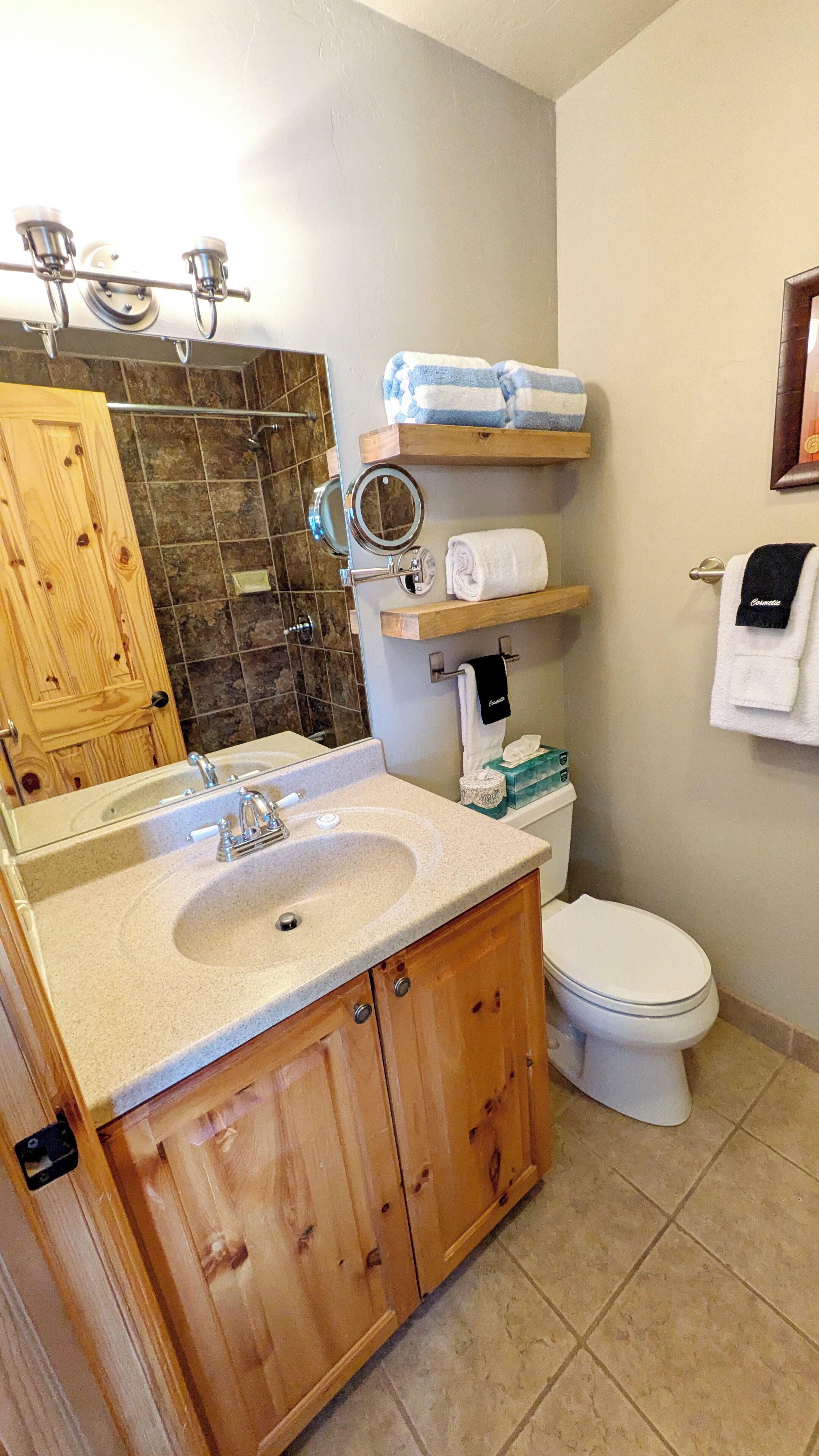 A bathroom with a wooden vanity, a sink, a toilet, and a shower area.