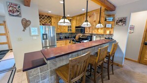A kitchen with wooden cabinets, stainless steel appliances, a granite countertop, and pendant lighting.