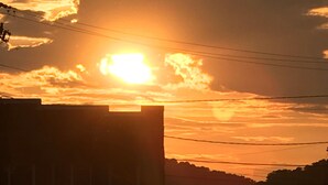 Ein Sonnenuntergang mit Wolken und Stromleitungen im Vordergrund.