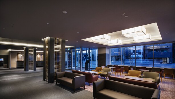 Um hall de hotel moderno com uma área de estar ampla, grandes janelas e design contemporâneo.