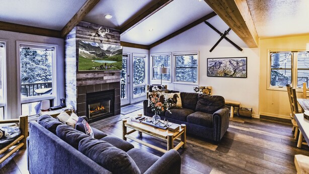 Una sala de estar acogedora con chimenea, ventanas amplias y un comedor.
