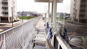 A balcony with a metal railing, a row of chairs, and a view of buildings in the background.