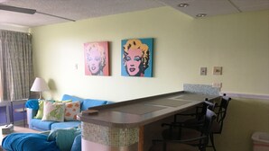 A room with a blue sofa, a small table, and two paintings on the wall.